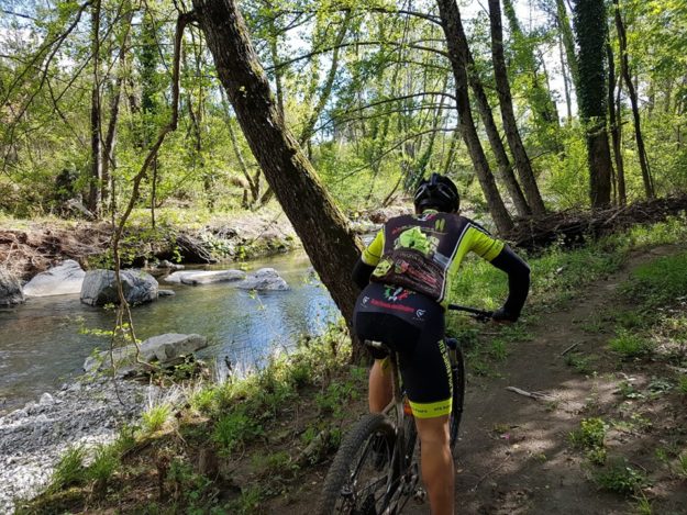 Un ciclista che si allena lungo le rive di un torrente