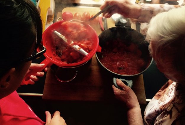 Una nonna e una nipote a fare insieme la salsa di pomodo